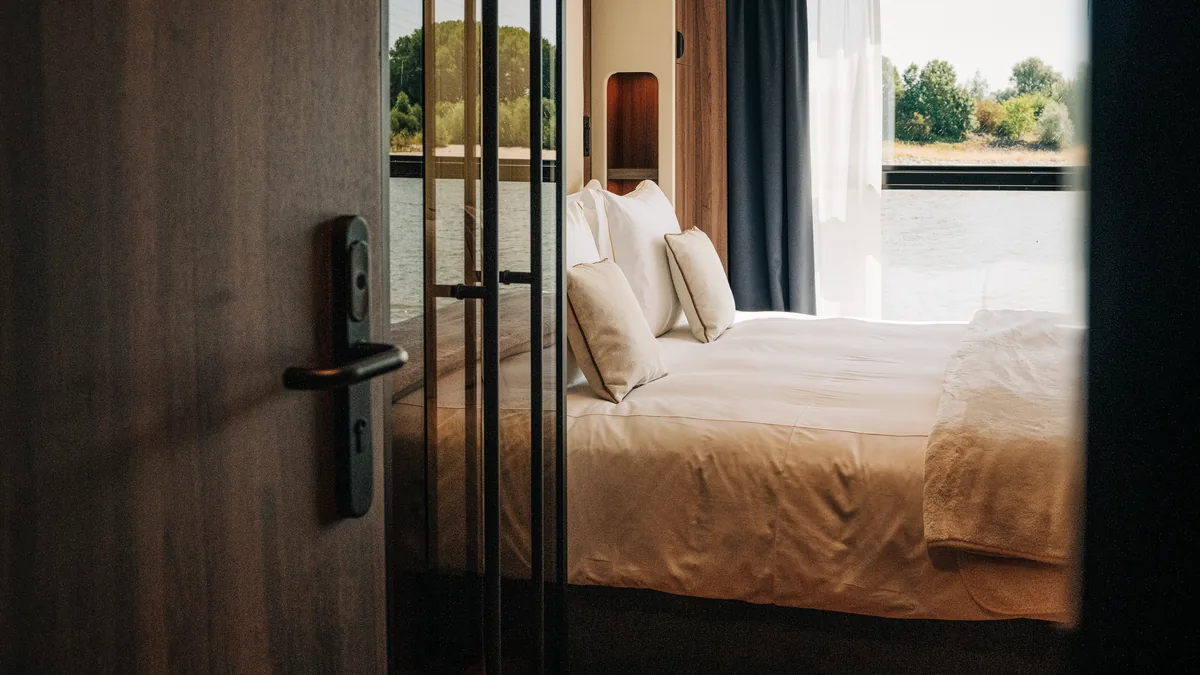 Cabine vue de l’entrée, avec très grand lit et vue sur la rivière